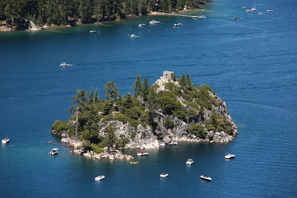 Fannette Island with the stone tea house ruin on its summit and small boats anchored around it in Emerald Bay